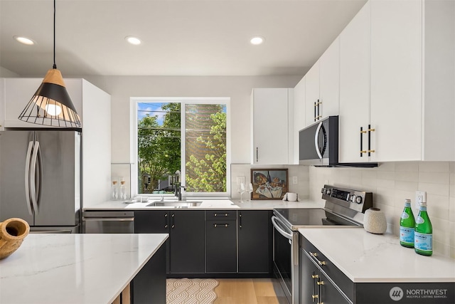 8513 19th Ave NW Unit A, Seattle, WA 98117 - kitchen featuring stainless steel appliances, a sink, white cabinets, dark cabinetry, and tasteful backsplash