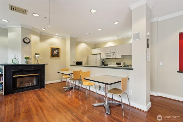 2415 2nd Ave Unit 543, Seattle, WA 98121 - kitchen featuring white appliances, ornamental molding, wood finished floors, baseboards, and dark countertops
