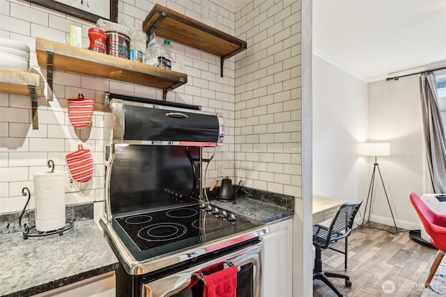 2415 2nd Ave Unit 543, Seattle, WA 98121 - kitchen with crown molding, stove, backsplash, light wood finished floors, and baseboards