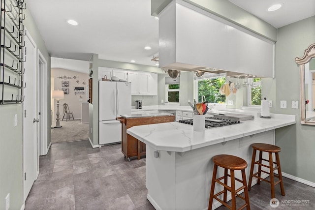 4628 109th Ave SE, Snohomish, WA 98290 - kitchen with stainless steel appliances, a peninsula, white cabinetry, recessed lighting, and a breakfast bar