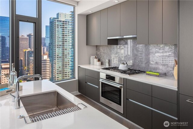 2510 6th Ave Unit 2802, Seattle, WA 98121 - kitchen with appliances with stainless steel finishes, gray cabinets, a sink, and backsplash