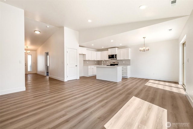 311 W Sandy Loop, Moses Lake, WA 98837 - unfurnished living room featuring a chandelier, lofted ceiling, recessed lighting, and light wood-style flooring