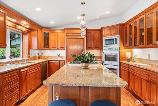 9317 192nd Pl SW, Edmonds, WA 98020 - kitchen featuring appliances with stainless steel finishes, a kitchen island, pendant lighting, light stone counters, and brown cabinets