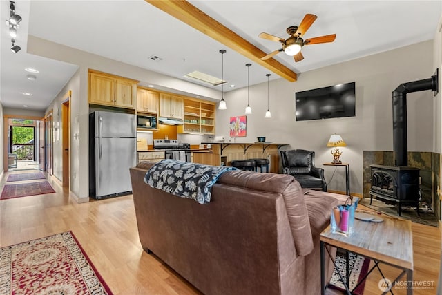 140 Twisp Ave W Unit 204, Twisp, WA 98856 - living area with beam ceiling, a wood stove, light wood finished floors, baseboards, and ceiling fan