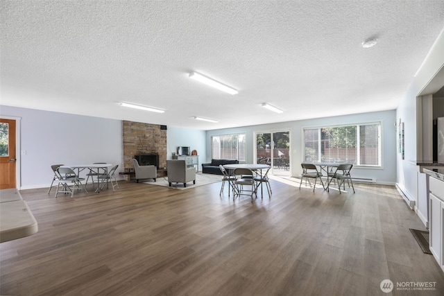 23708 Locust Way Unit 26B, Bothell, WA 98021 - living area featuring a textured ceiling, a stone fireplace, wood finished floors, healthy amount of natural light, and baseboards