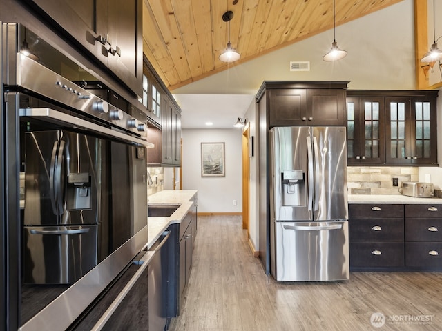 957 SW Camano Dr, Camano Island, WA 98282 - kitchen with appliances with stainless steel finishes, dark brown cabinets, glass insert cabinets, backsplash, and lofted ceiling