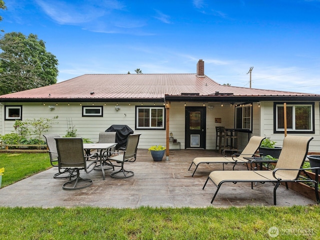 957 SW Camano Dr, Camano Island, WA 98282 - rear view of house featuring a patio area, metal roof, and a chimney