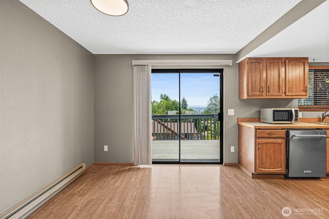 7391 E Grandview St, Port Orchard, WA 98366 - kitchen featuring appliances with stainless steel finishes, a baseboard radiator, light wood finished floors, brown cabinets, and a textured ceiling
