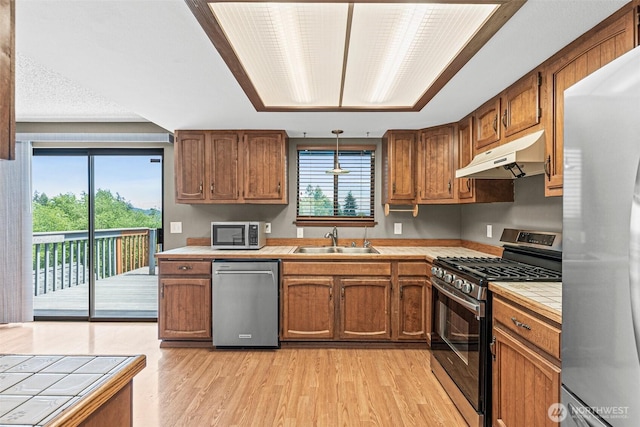 7391 E Grandview St, Port Orchard, WA 98366 - kitchen featuring appliances with stainless steel finishes, under cabinet range hood, tile counters, a sink, and light wood-style floors