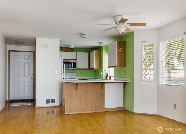 730 SE 8th Ave Unit B101, Oak Harbor, WA 98277 - kitchen featuring stainless steel microwave, stove, light wood-style flooring, light countertops, and a kitchen breakfast bar