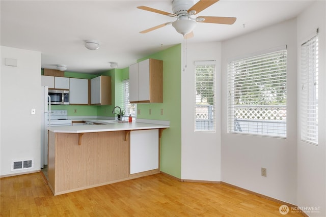730 SE 8th Ave Unit B101, Oak Harbor, WA 98277 - kitchen with stainless steel microwave, white electric range oven, light wood-style flooring, and a kitchen breakfast bar
