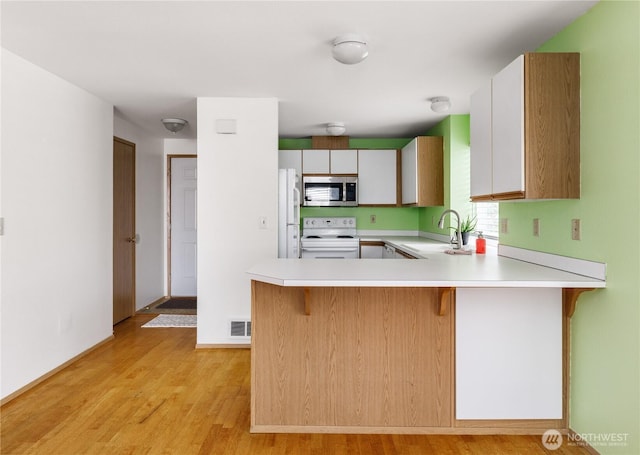 730 SE 8th Ave Unit B101, Oak Harbor, WA 98277 - kitchen with white appliances, light countertops, a sink, light wood-type flooring, and a kitchen bar