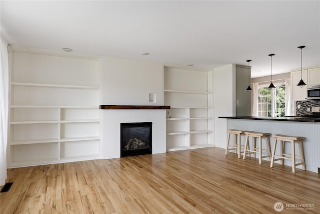 1020 SW Bowmer St, Oak Harbor, WA 98277 - unfurnished living room featuring light wood-style flooring, a glass covered fireplace, and built in shelves