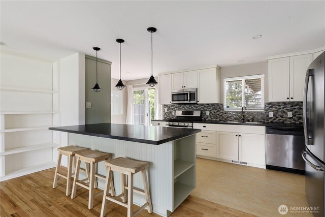 1020 SW Bowmer St, Oak Harbor, WA 98277 - kitchen featuring appliances with stainless steel finishes, a sink, dark countertops, tasteful backsplash, and light wood-style floors