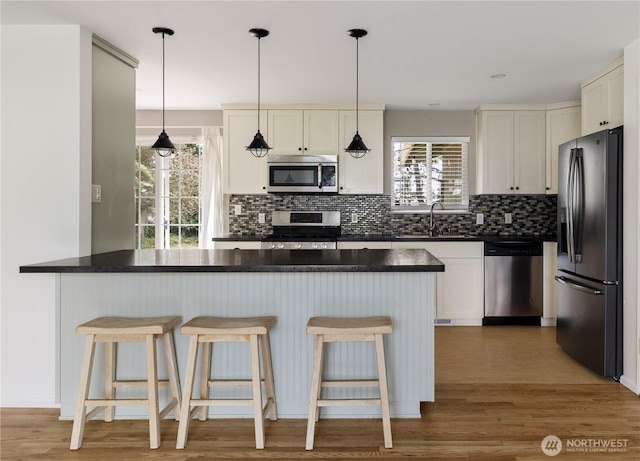 1020 SW Bowmer St, Oak Harbor, WA 98277 - kitchen featuring appliances with stainless steel finishes, dark countertops, tasteful backsplash, and light wood-type flooring