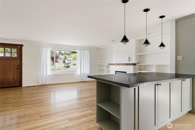 1020 SW Bowmer St, Oak Harbor, WA 98277 - kitchen featuring dark countertops, open shelves, light wood-type flooring, a fireplace, and hanging light fixtures