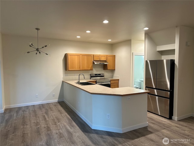 9614 191st Street Ct E, Puyallup, WA 98375 - kitchen featuring appliances with stainless steel finishes, a sink, under cabinet range hood, dark wood finished floors, and light countertops