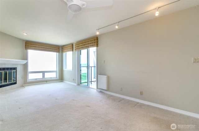 1526 Alki Ave SW Unit 303, Seattle, WA 98116 - unfurnished living room with rail lighting, ceiling fan, carpet floors, and a fireplace