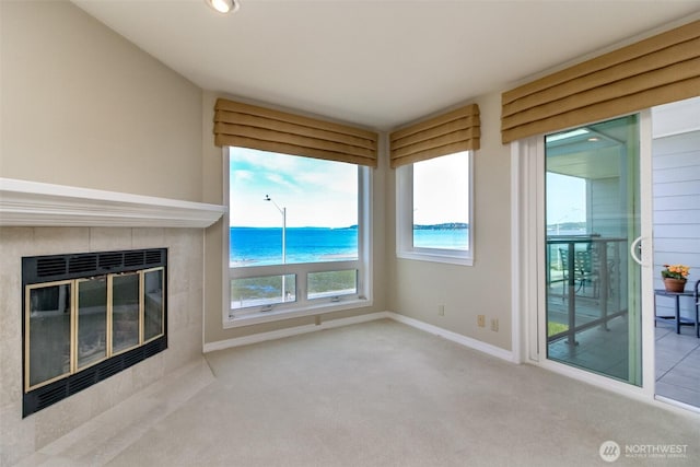 1526 Alki Ave SW Unit 303, Seattle, WA 98116 - unfurnished living room featuring carpet flooring, baseboards, a tile fireplace, and a water view