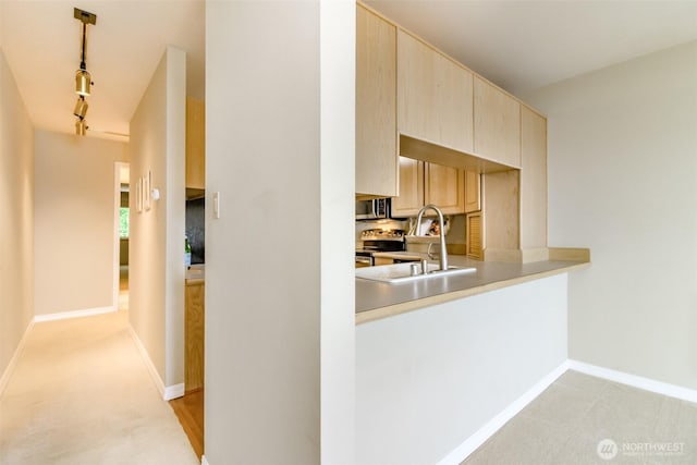 1526 Alki Ave SW Unit 303, Seattle, WA 98116 - kitchen featuring appliances with stainless steel finishes, track lighting, light brown cabinets, light countertops, and baseboards