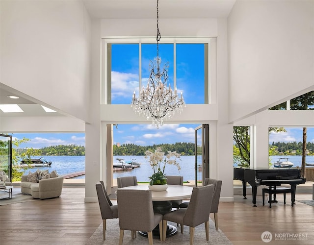 8620 N Mercer Way, Mercer Island, WA 98040 - dining room featuring a chandelier, wood finished floors, a water view, and a high ceiling