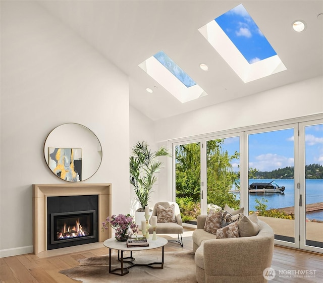 8620 N Mercer Way, Mercer Island, WA 98040 - living room featuring a skylight, light wood-type flooring, a fireplace with flush hearth, a water view, and high vaulted ceiling