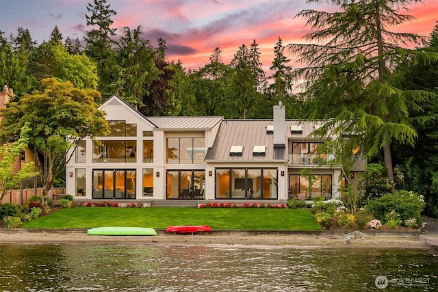8620 N Mercer Way, Mercer Island, WA 98040 - back of house at dusk featuring a balcony, a standing seam roof, a chimney, a water view, and metal roof