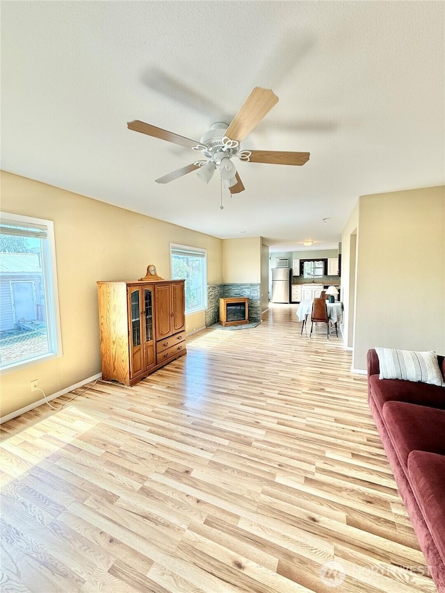 926 S 4th Ave, Okanogan, WA 98840 - living area with ceiling fan, a glass covered fireplace, light wood-style floors, and baseboards