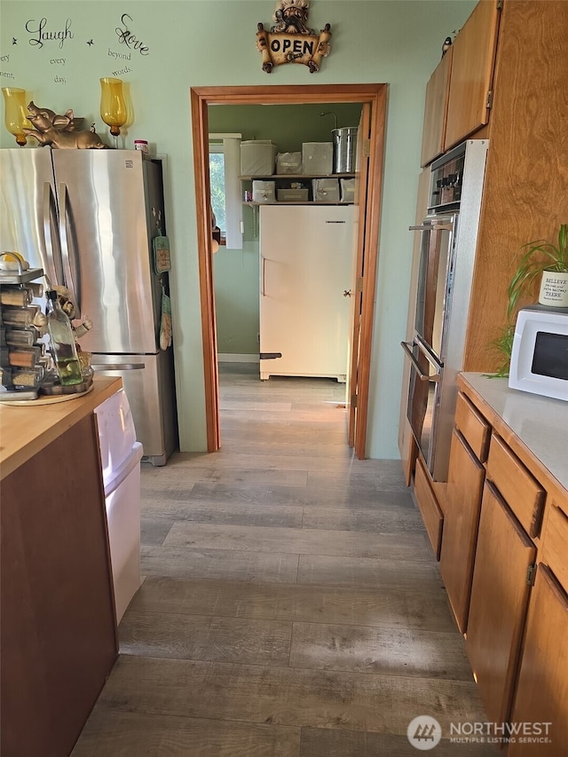 208 N Broadway St, Westport, WA 98595 - kitchen featuring appliances with stainless steel finishes, wood finished floors, light countertops, and brown cabinetry