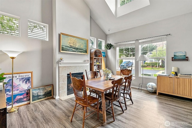 6499 Francis Loop SE, Auburn, WA 98092 - dining area featuring high vaulted ceiling, wood finished floors, a fireplace, baseboards, and a skylight