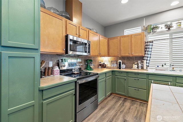 6499 Francis Loop SE, Auburn, WA 98092 - kitchen featuring appliances with stainless steel finishes, tile counters, green cabinets, a sink, and tasteful backsplash