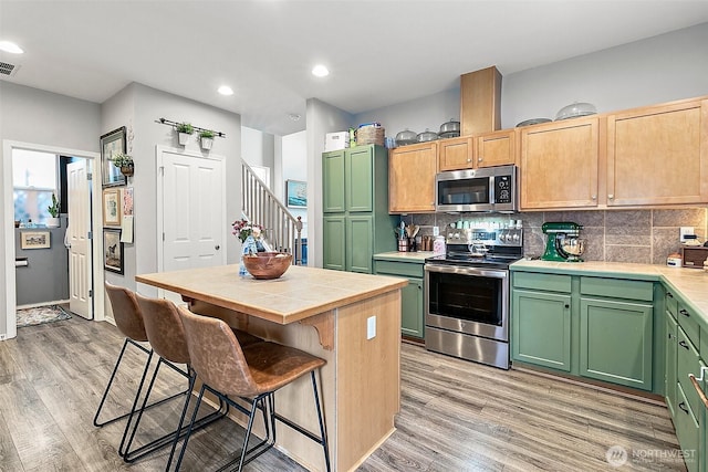 6499 Francis Loop SE, Auburn, WA 98092 - kitchen featuring appliances with stainless steel finishes, light wood-type flooring, a kitchen breakfast bar, backsplash, and recessed lighting