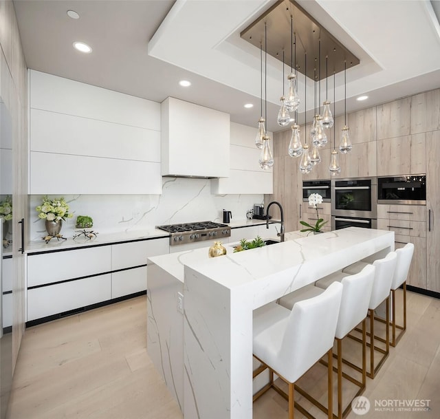 17281 SE 43rd St, Bellevue, WA 98006 - kitchen featuring modern cabinets, stainless steel appliances, a tray ceiling, recessed lighting, and a large island with sink