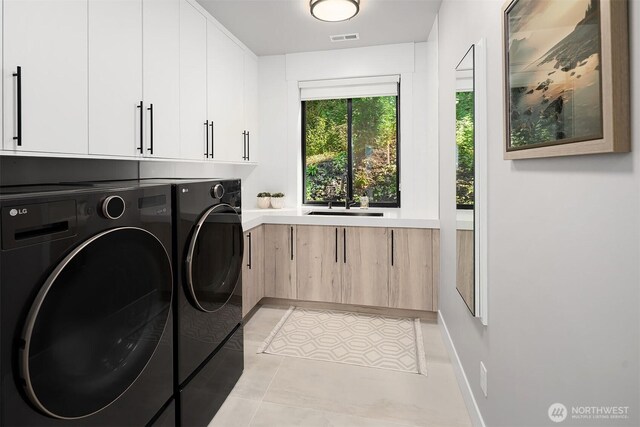 17281 SE 43rd St, Bellevue, WA 98006 - washroom featuring washing machine and dryer, cabinet space, and light tile patterned flooring