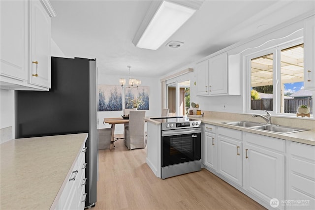 1013 21st St NW, Puyallup, WA 98371 - kitchen with appliances with stainless steel finishes, light wood-type flooring, white cabinets, a chandelier, and light countertops