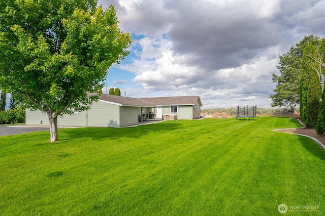 12009 NW Dodson Rd, Ephrata, WA 98823 - view of grassy yard with a trampoline and a patio
