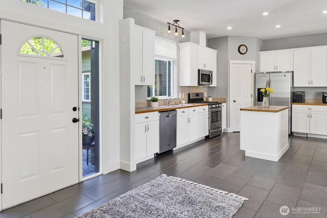 1055 Falls Dr, Bellingham, WA 98229 - kitchen featuring appliances with stainless steel finishes, decorative backsplash, a sink, a center island, and white cabinetry