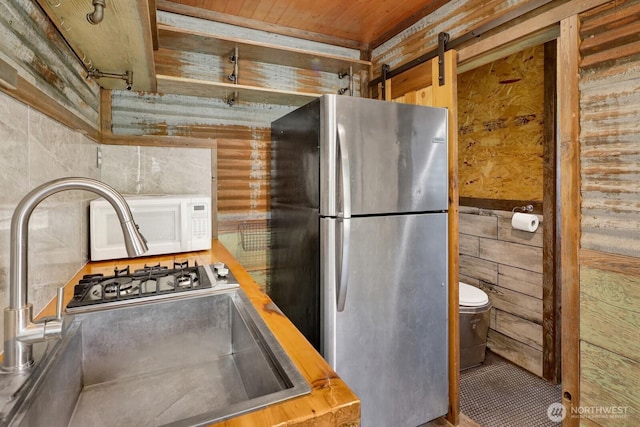 1055 Falls Dr, Bellingham, WA 98229 - kitchen featuring freestanding refrigerator, wooden ceiling, a sink, wooden walls, and white microwave