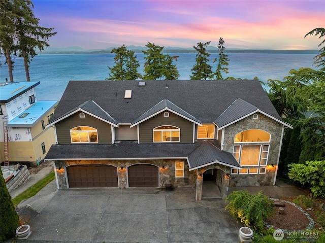 699 Lehman Dr, Camano Island, WA 98282 - view of front of home with stone siding, a garage, concrete driveway, and a water view