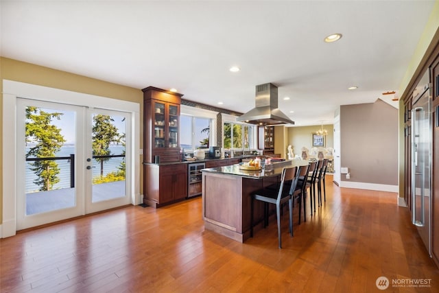 699 Lehman Dr, Camano Island, WA 98282 - kitchen featuring island range hood, a kitchen breakfast bar, glass insert cabinets, a kitchen island, and wood-type flooring