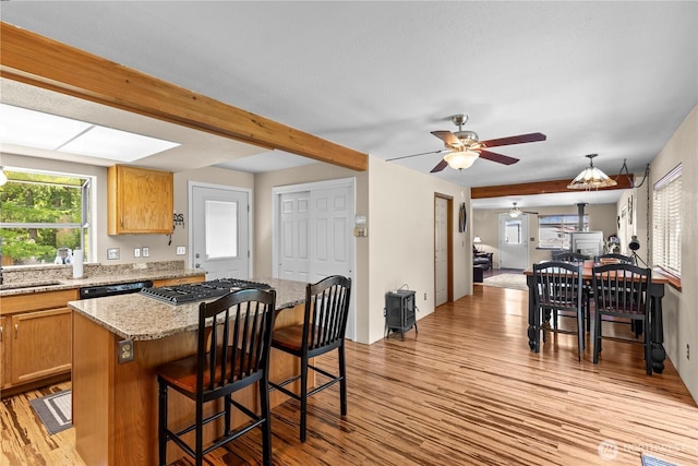 51 Deer Meadow Ln, Naches, WA 98937 - kitchen featuring light wood-style floors, a kitchen island, stainless steel gas stovetop, a kitchen breakfast bar, and light stone countertops