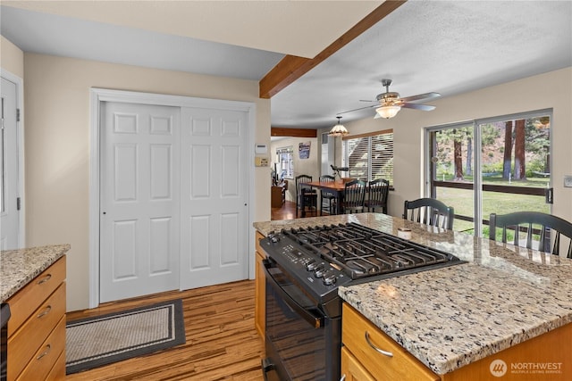 51 Deer Meadow Ln, Naches, WA 98937 - kitchen with black range with gas cooktop, light wood-style floors, a ceiling fan, light stone countertops, and a center island