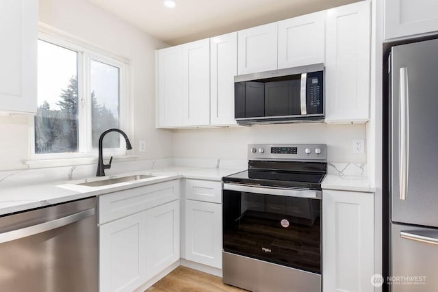 8823 Holly Dr Unit G205, Everett, WA 98208 - kitchen with appliances with stainless steel finishes, a sink, white cabinets, and light stone counters
