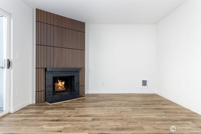 8823 Holly Dr Unit G205, Everett, WA 98208 - unfurnished living room with wood finished floors, a fireplace with flush hearth, and baseboards