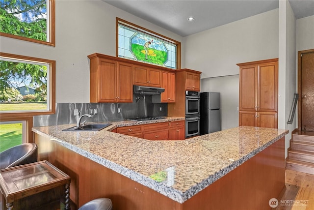 3726 SW 313th St, Federal Way, WA 98023 - kitchen featuring stainless steel appliances, a high ceiling, under cabinet range hood, brown cabinetry, and light wood finished floors