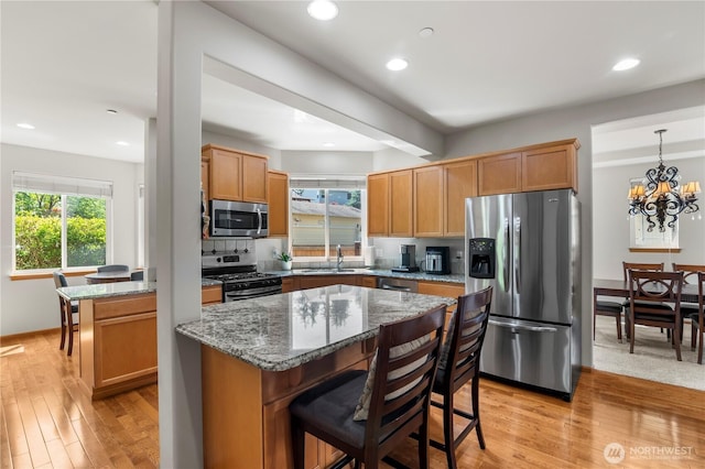 2903 96th St SE, Everett, WA 98208 - kitchen featuring stainless steel appliances, a breakfast bar area, light wood finished floors, a chandelier, and stone countertops