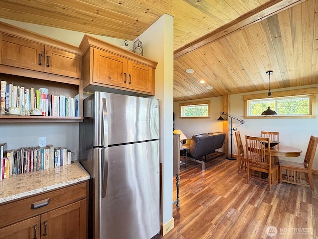 1068 Happy Valley Rd, Sequim, WA 98382 - kitchen featuring freestanding refrigerator, wood ceiling with exposed beams, brown cabinetry, light wood-style flooring, and light stone countertops