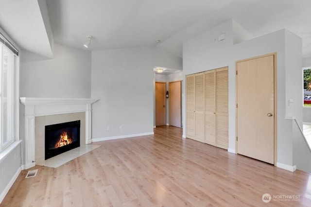 10903 Paine Field Way, Everett, WA 98204 - unfurnished living room featuring a tile fireplace, lofted ceiling, wood finished floors, and baseboards