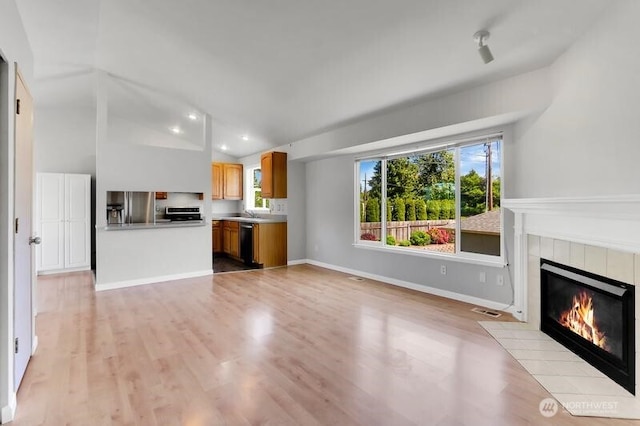 10903 Paine Field Way, Everett, WA 98204 - unfurnished living room with a tiled fireplace, light wood-style flooring, recessed lighting, and baseboards
