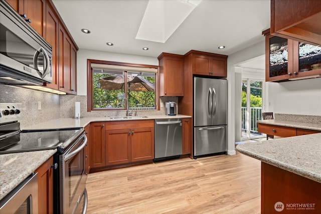 9 199th Pl SE, Bothell, WA 98012 - kitchen with appliances with stainless steel finishes, a sink, a skylight, light wood finished floors, and tasteful backsplash